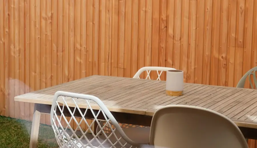 Holzterrasse mit Gartenmöbeln vor einem Holzzaun – Terrassen und Wege